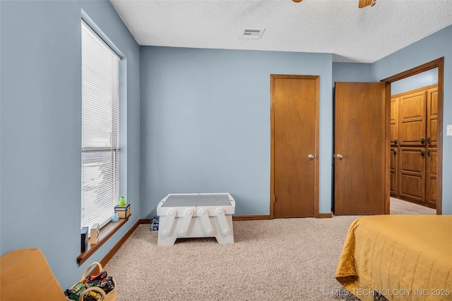 bedroom featuring a textured ceiling, light colored carpet, and ceiling fan