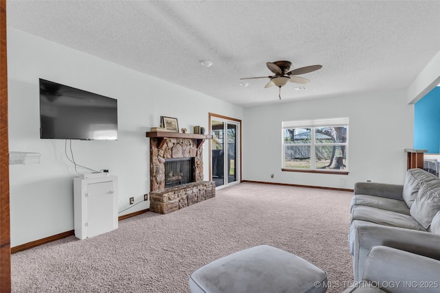 living room with carpet floors, ceiling fan, a textured ceiling, and a stone fireplace