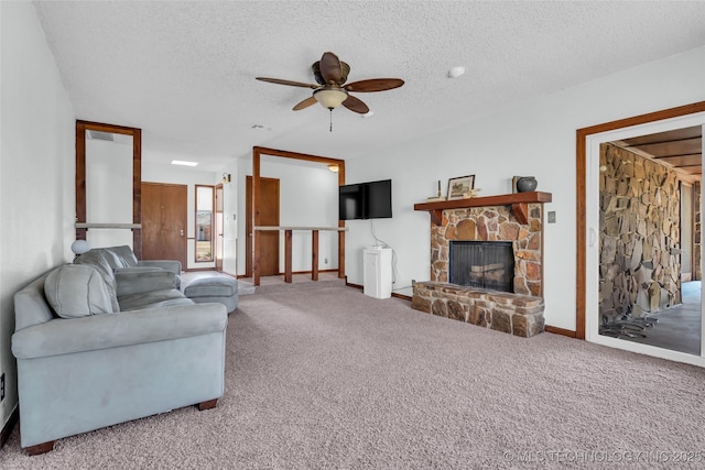 carpeted living room with a textured ceiling, ceiling fan, and a stone fireplace