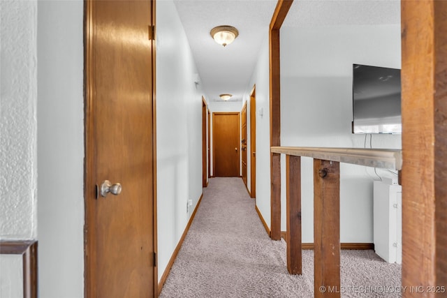 corridor featuring light carpet and a textured ceiling