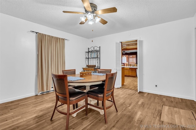 dining room featuring a textured ceiling, ceiling fan, and light wood-type flooring