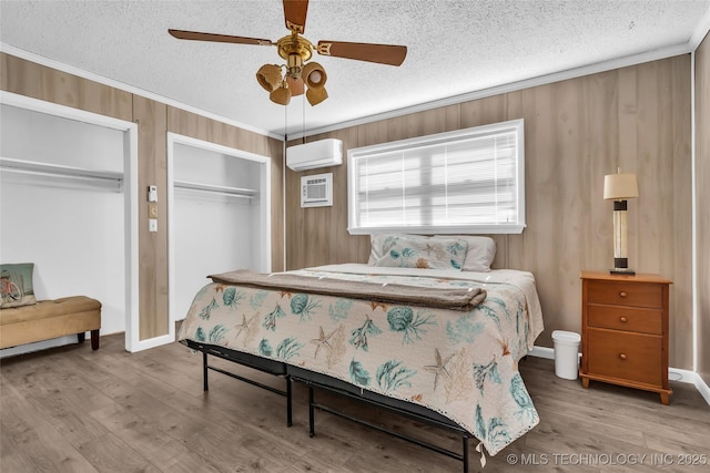 bedroom featuring an AC wall unit, a textured ceiling, ceiling fan, ornamental molding, and wood-type flooring