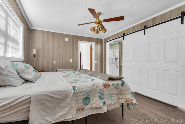 bedroom featuring ornamental molding, a textured ceiling, ceiling fan, and a barn door