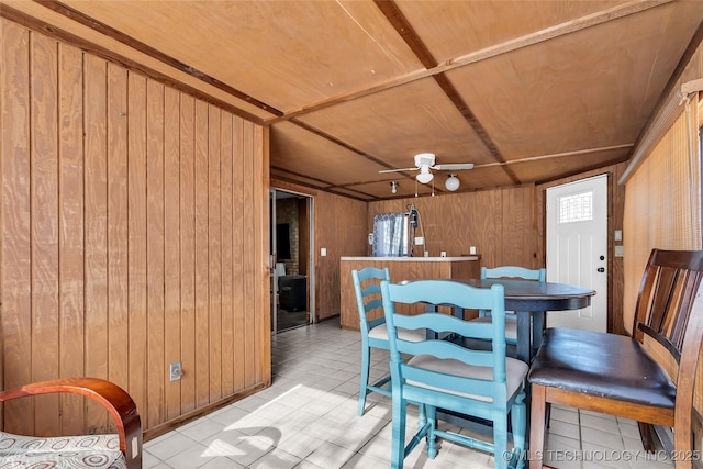 tiled dining room featuring ceiling fan, wooden ceiling, and wood walls