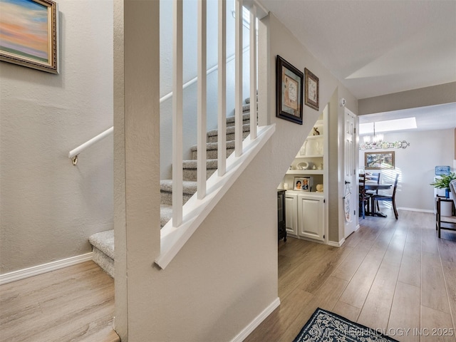 stairway with hardwood / wood-style flooring and an inviting chandelier