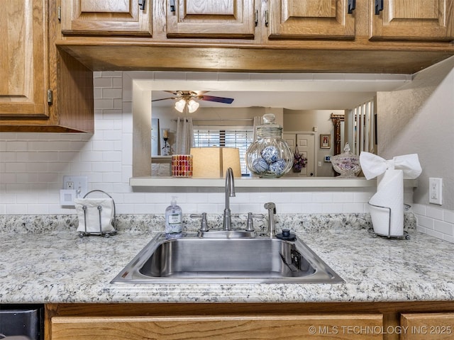 interior details featuring light stone countertops, ceiling fan, backsplash, and sink