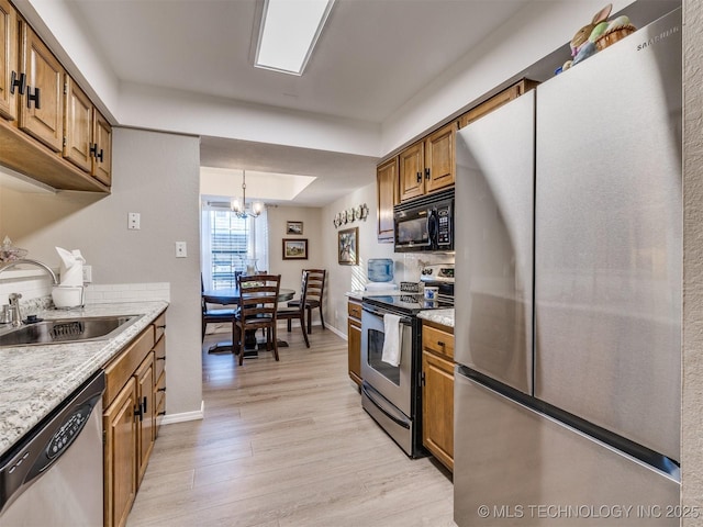 kitchen featuring stainless steel appliances, sink, light hardwood / wood-style floors, a chandelier, and pendant lighting