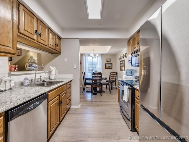 kitchen with stainless steel appliances, sink, light hardwood / wood-style flooring, a chandelier, and pendant lighting