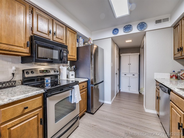 kitchen with stainless steel appliances, backsplash, light hardwood / wood-style floors, and light stone counters