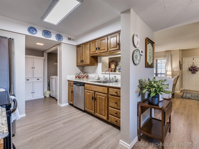 kitchen with sink, a textured ceiling, light hardwood / wood-style floors, and appliances with stainless steel finishes