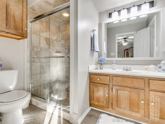 bathroom with toilet, vanity, ceiling fan, and a shower with shower door