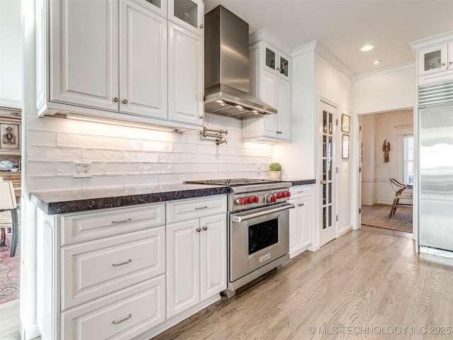 kitchen featuring white cabinets, wall chimney exhaust hood, high end appliances, light hardwood / wood-style flooring, and crown molding