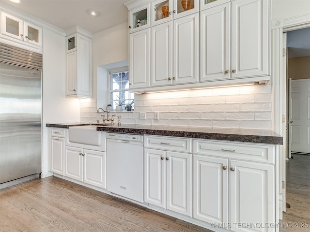 kitchen featuring dishwasher, stainless steel built in fridge, sink, white cabinets, and backsplash