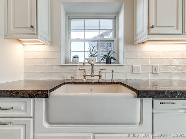 kitchen featuring sink, white cabinets, decorative backsplash, and dark stone countertops