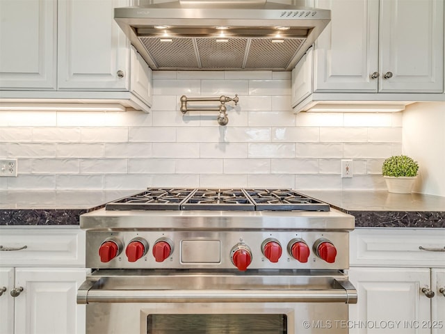 kitchen featuring exhaust hood, white cabinets, dark stone countertops, backsplash, and high end stove