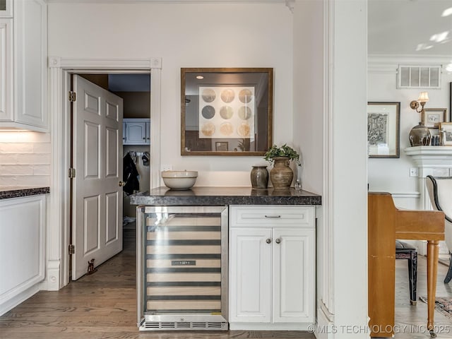 bar featuring tasteful backsplash, white cabinets, ornamental molding, light hardwood / wood-style flooring, and wine cooler