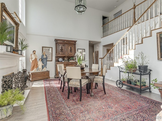 dining space featuring a chandelier, a towering ceiling, and light wood-type flooring