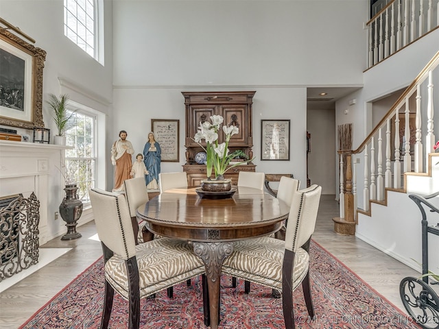 dining space with light hardwood / wood-style floors, a wealth of natural light, and a towering ceiling