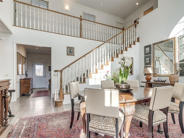 dining area with light hardwood / wood-style flooring, a towering ceiling, and ornamental molding