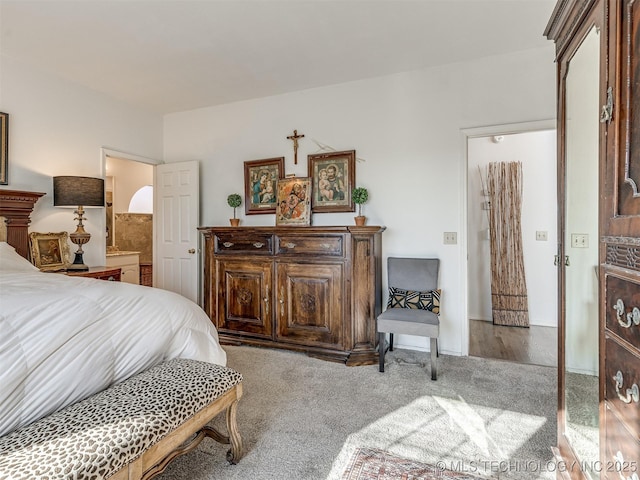 bedroom featuring connected bathroom and light carpet