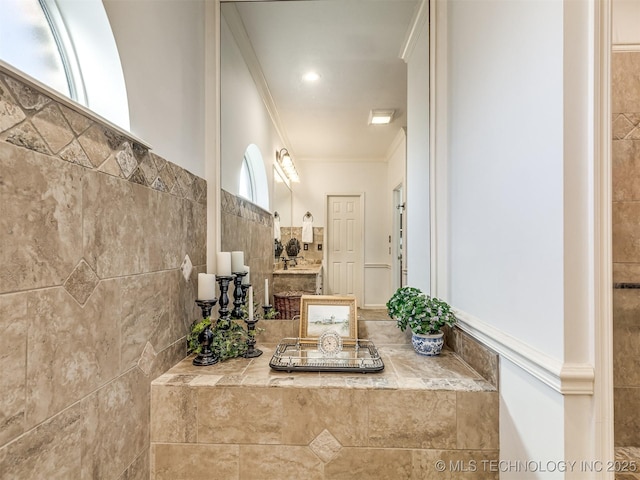 bathroom with vanity, crown molding, and tile walls