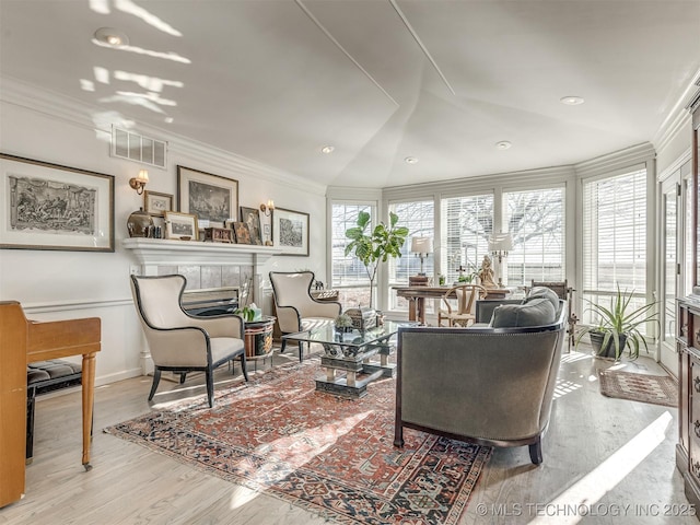 living room with a fireplace, light hardwood / wood-style flooring, lofted ceiling, and crown molding