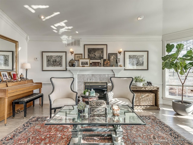 sitting room with wood-type flooring, crown molding, and a fireplace