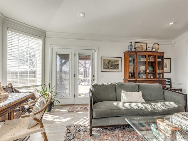 living room featuring vaulted ceiling, ornamental molding, and light wood-type flooring