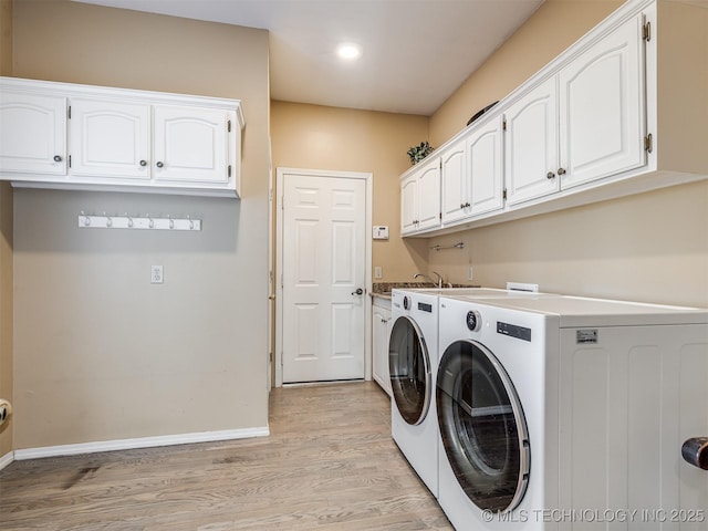 washroom with cabinets, light wood-type flooring, and washing machine and clothes dryer