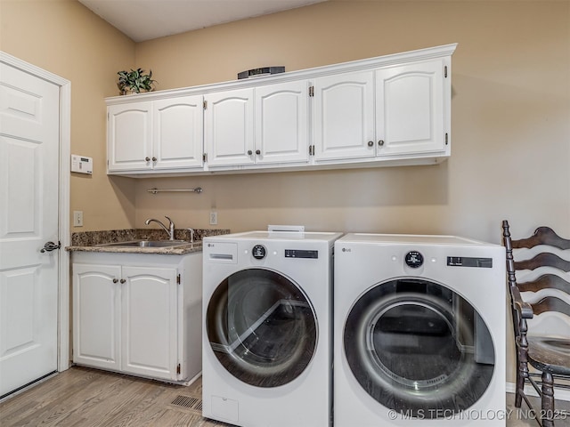 washroom featuring sink, cabinets, light hardwood / wood-style flooring, and washing machine and dryer