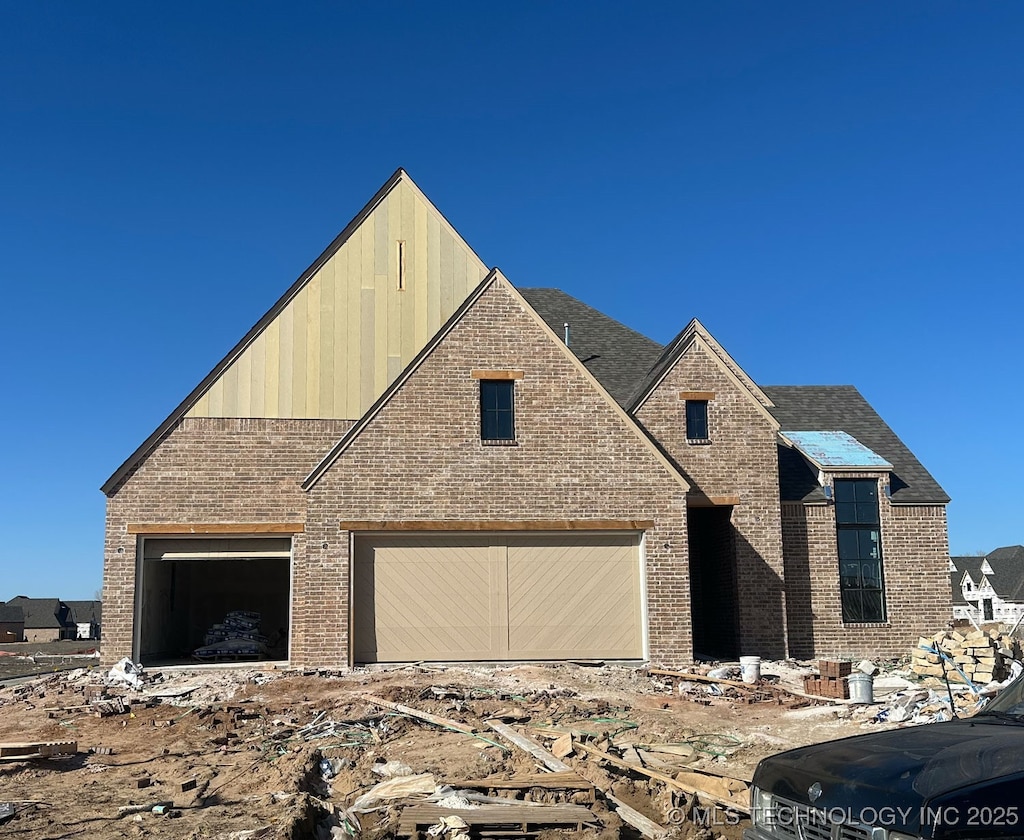 view of front facade with a garage, brick siding, and roof with shingles