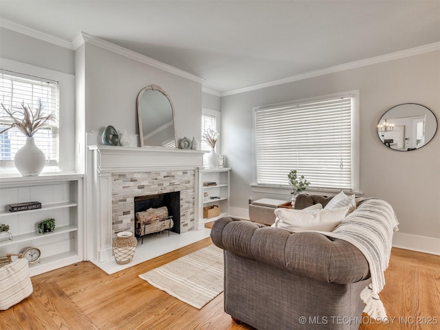 living room with a tiled fireplace, light hardwood / wood-style floors, ornamental molding, and a wealth of natural light