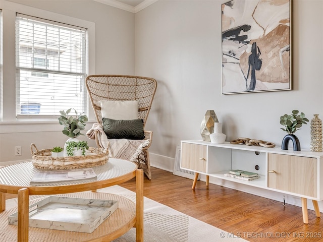 living area with hardwood / wood-style flooring and crown molding