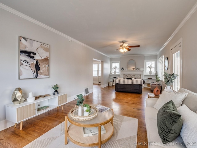 living room with wood-type flooring, ceiling fan, crown molding, and a healthy amount of sunlight