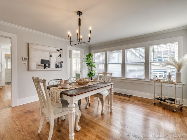 dining room featuring crown molding, a chandelier, and hardwood / wood-style flooring