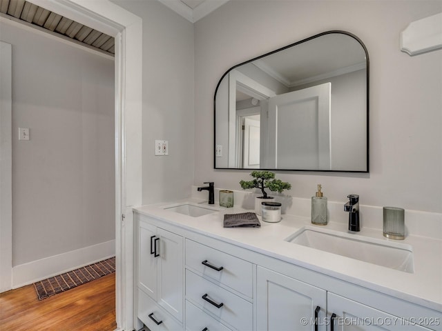 bathroom with crown molding, wood-type flooring, and vanity