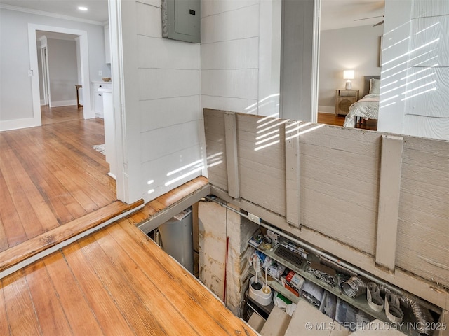 interior details with electric panel, ornamental molding, and wood-type flooring