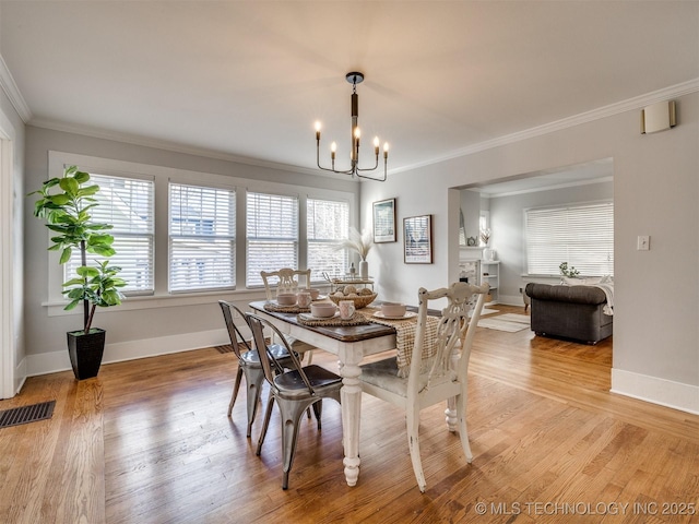 dining area featuring an inviting chandelier, ornamental molding, and light hardwood / wood-style flooring