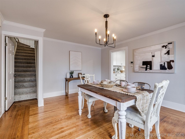 dining room featuring light wood-type flooring, a notable chandelier, and crown molding