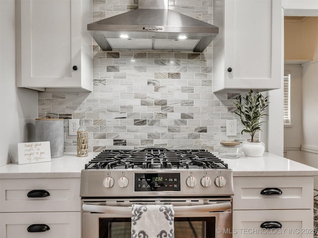 kitchen with backsplash, wall chimney range hood, stainless steel range with gas stovetop, and white cabinetry