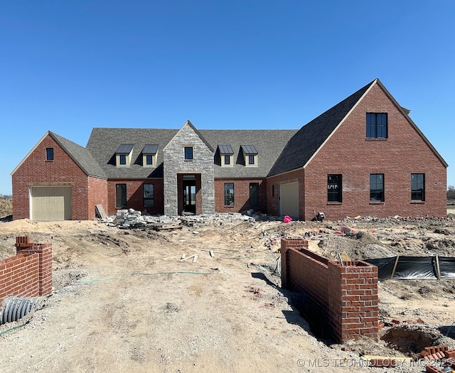 view of front of house featuring brick siding, stone siding, and a garage