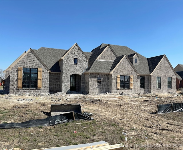 view of front of home featuring brick siding, stone siding, and roof with shingles