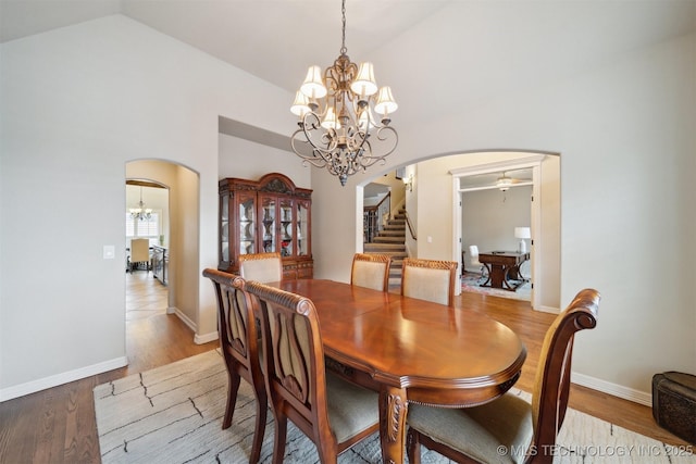 dining area featuring light hardwood / wood-style flooring, lofted ceiling, and ceiling fan with notable chandelier