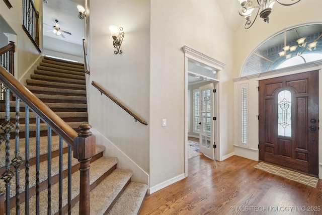 entryway featuring a high ceiling, ceiling fan with notable chandelier, and hardwood / wood-style flooring