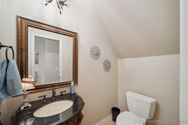 bathroom featuring sink, vaulted ceiling, and toilet