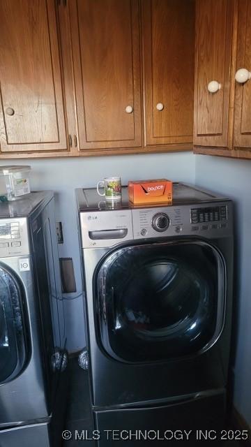 clothes washing area with cabinets and washing machine and clothes dryer