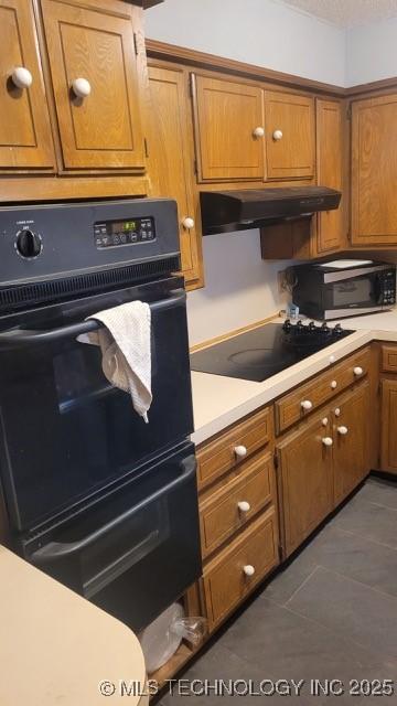 kitchen with dark tile patterned floors and black appliances