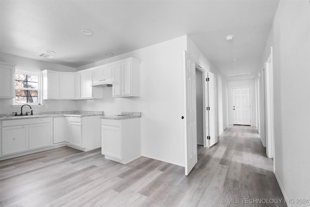 kitchen featuring white cabinets, light wood-type flooring, and sink