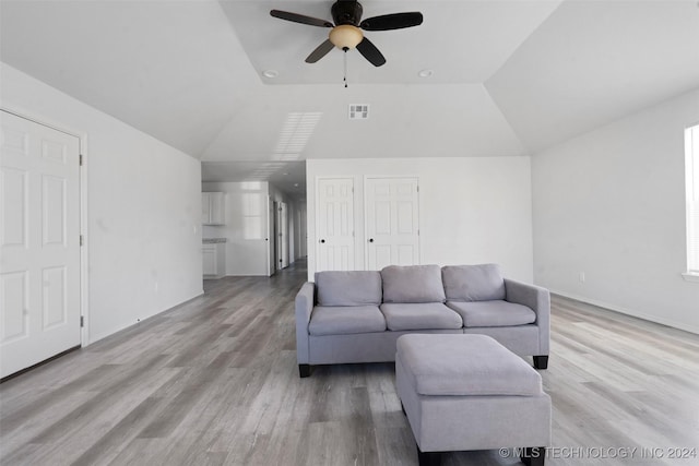 living room featuring ceiling fan, light hardwood / wood-style floors, and vaulted ceiling