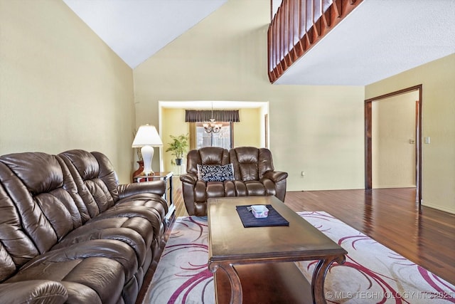 living room with a notable chandelier, hardwood / wood-style floors, and lofted ceiling